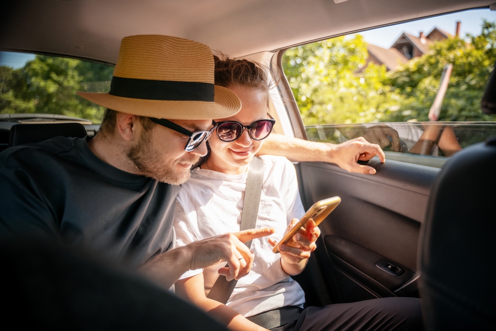 Young,cheerful,happy,couple,of,travelers,sitting,in,car,looking